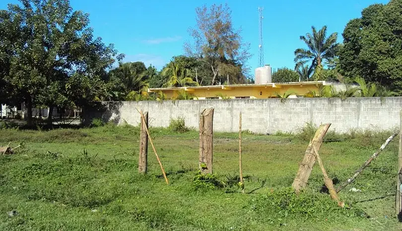 Fenced corner lot with green grass in Barrio Venecia, Tela