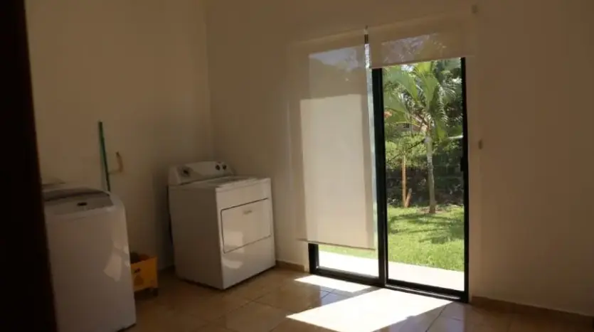 Área de lavandería con puerta de vidrio al jardín en la casa de Trujillo