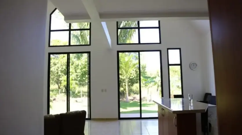 Sala de techo alto con grandes ventanales en la casa de Trujillo
