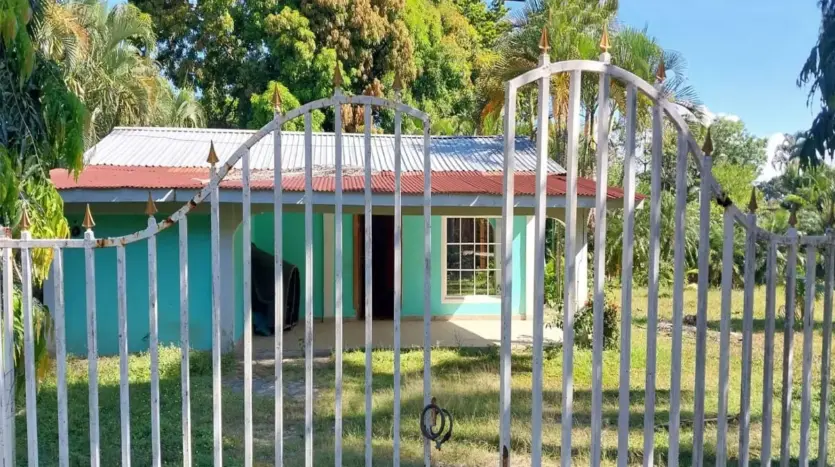 Gate and turquoise house on the property in Piedra Pintada, La Ceiba