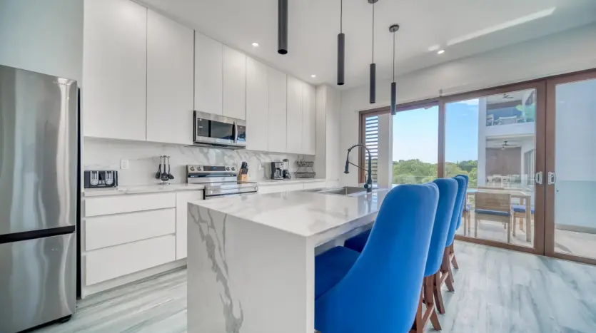 Cocina con isla de cuarzo en cascada y electrodomésticos de acero inoxidable