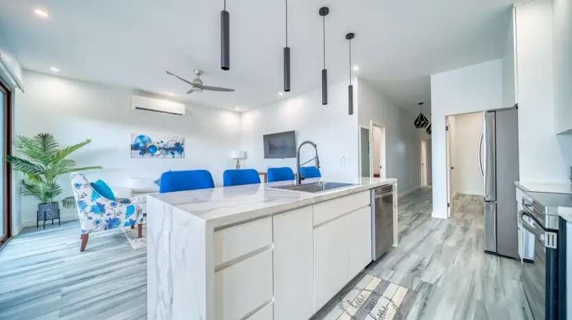 Isla de cocina con bancos de bar mirando hacia la sala