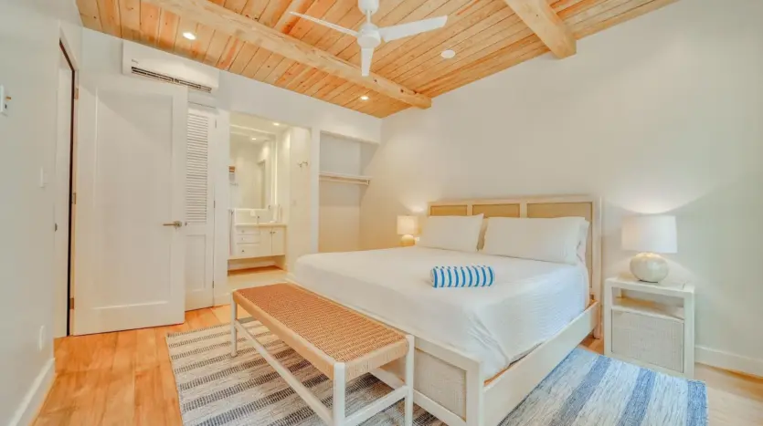 Primary bedroom with wood-beam ceiling, sample unit